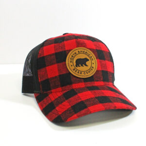Red and black plaid hat with black mesh on the back and brown circle label with North American Bear Center etched in.